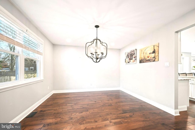 unfurnished dining area with a chandelier and dark hardwood / wood-style floors