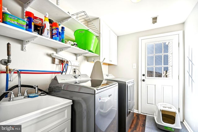 laundry area featuring washer and dryer, sink, cabinets, and dark hardwood / wood-style floors