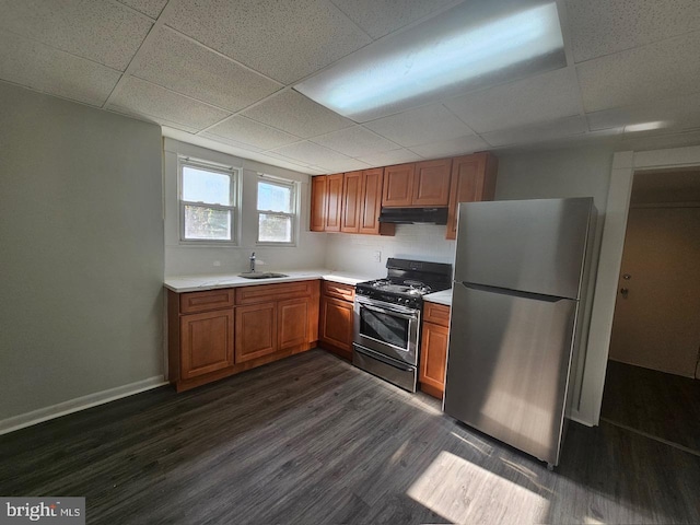 kitchen with a drop ceiling, sink, stainless steel appliances, and dark wood-type flooring