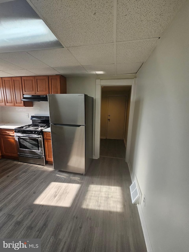 kitchen featuring appliances with stainless steel finishes, light hardwood / wood-style floors, and a drop ceiling