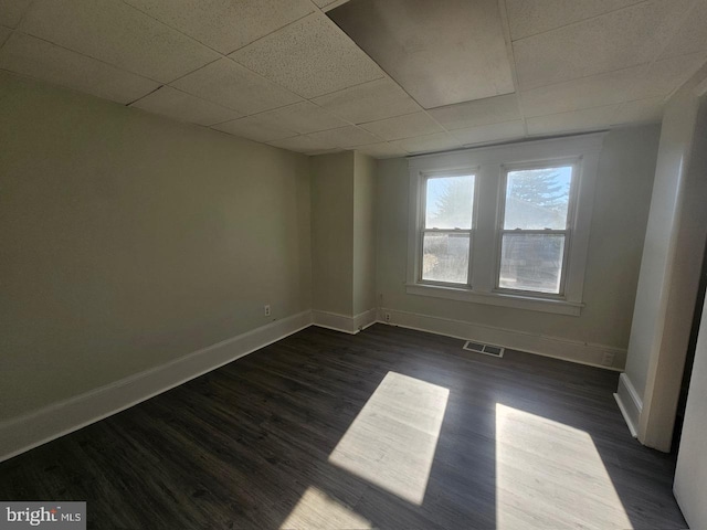 unfurnished room with a paneled ceiling and dark hardwood / wood-style floors