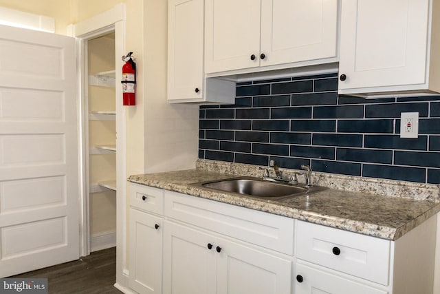 kitchen with decorative backsplash, white cabinetry, sink, and dark wood-type flooring