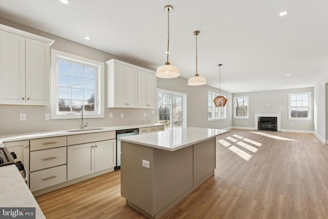 kitchen featuring dishwasher, white cabinets, sink, hanging light fixtures, and a kitchen island