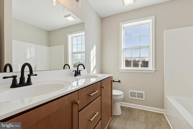 bathroom featuring vanity, a healthy amount of sunlight, and toilet