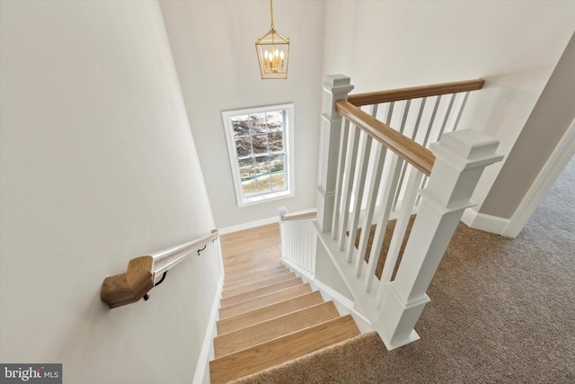 stairway with carpet floors and a notable chandelier