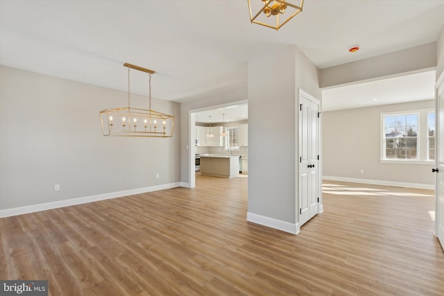 empty room with a chandelier and light hardwood / wood-style flooring