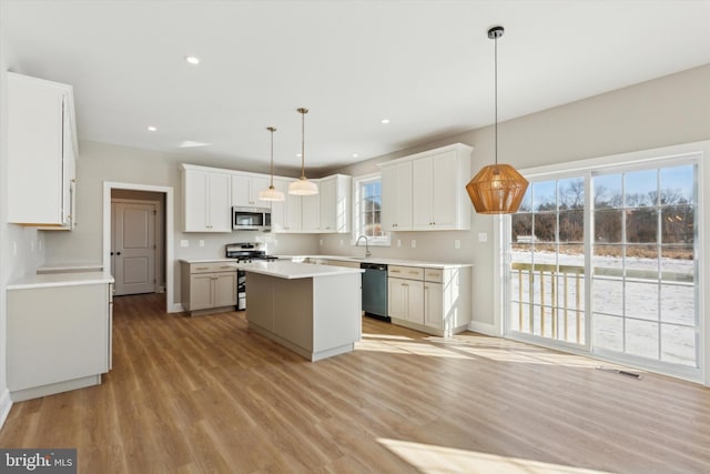 kitchen with white cabinets, a center island, appliances with stainless steel finishes, and pendant lighting