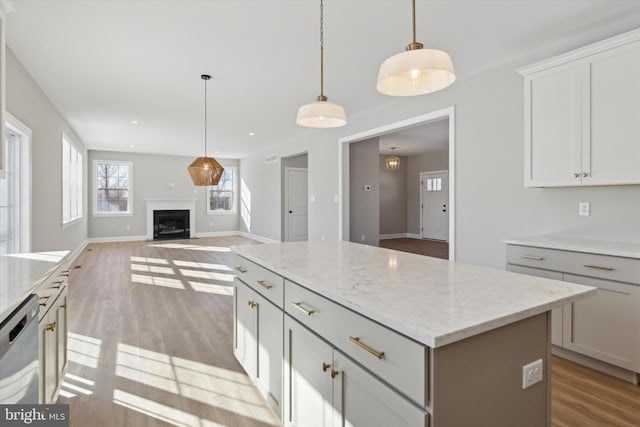 kitchen with pendant lighting, light hardwood / wood-style floors, stainless steel dishwasher, and a kitchen island