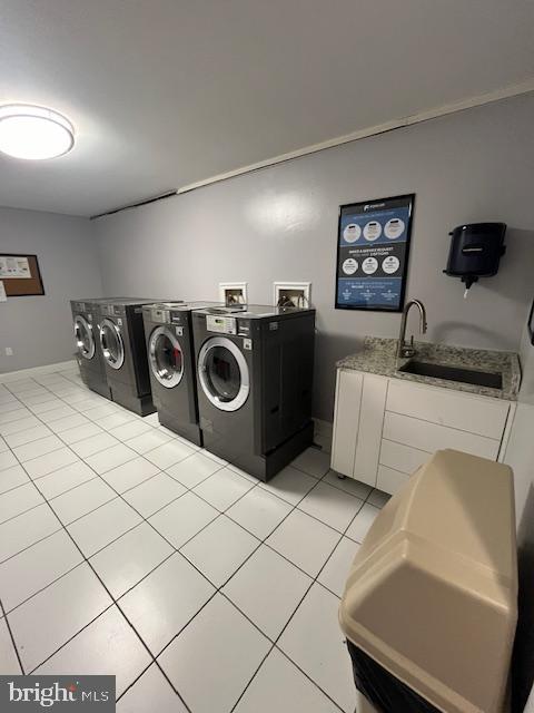 clothes washing area featuring light tile patterned floors, independent washer and dryer, and cabinet space