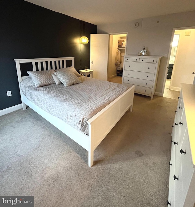 bedroom featuring a walk in closet, a closet, and light colored carpet