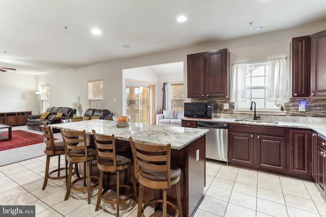 kitchen featuring dishwasher, decorative backsplash, a kitchen island, and a breakfast bar area