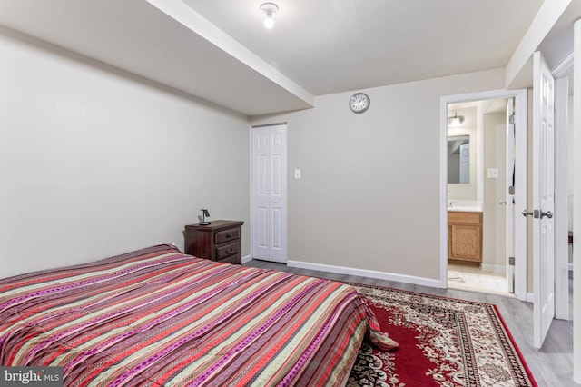 bedroom featuring connected bathroom and light hardwood / wood-style floors