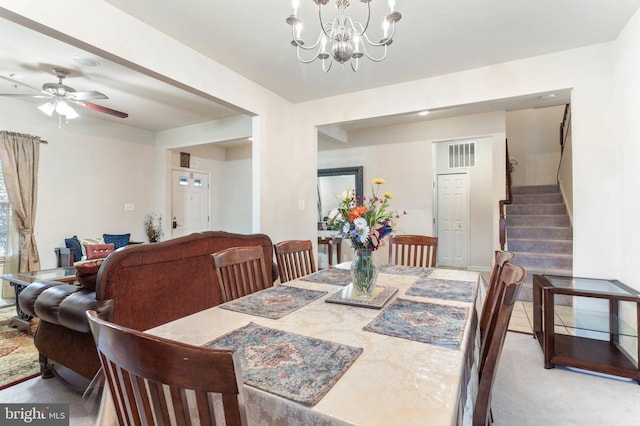 dining room featuring light colored carpet and ceiling fan with notable chandelier