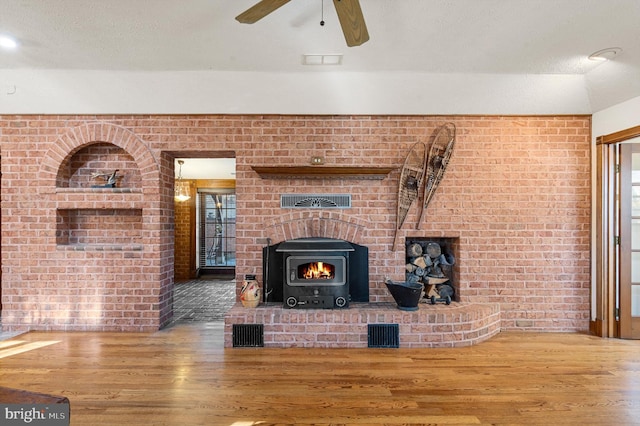 living room with hardwood / wood-style flooring, ceiling fan, a textured ceiling, and brick wall