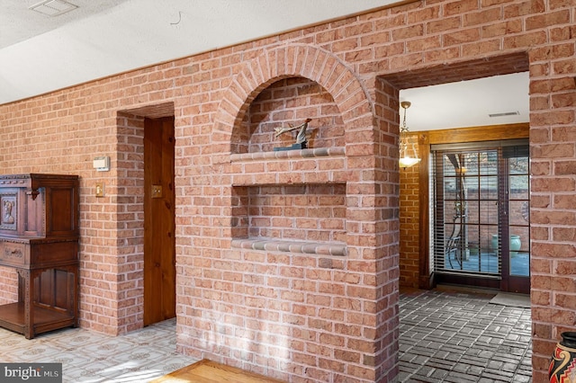 interior space featuring a textured ceiling and brick wall