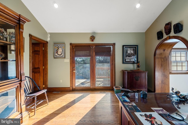 office space with a healthy amount of sunlight, lofted ceiling, and light hardwood / wood-style flooring