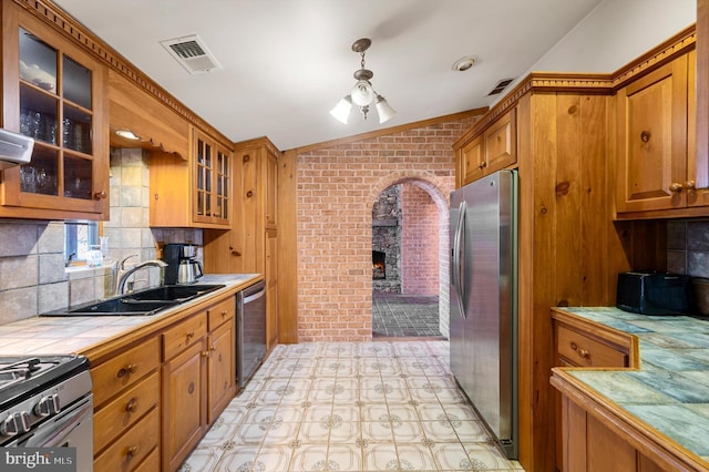 kitchen with decorative backsplash, stainless steel appliances, sink, tile counters, and lofted ceiling