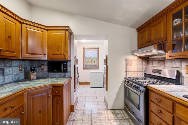 kitchen with gas stove, tile countertops, decorative backsplash, and vaulted ceiling