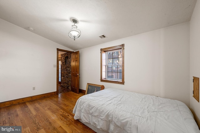 bedroom featuring a textured ceiling, lofted ceiling, and hardwood / wood-style flooring