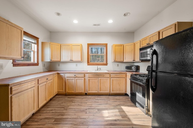 kitchen with light brown cabinets, sink, light hardwood / wood-style floors, and black appliances