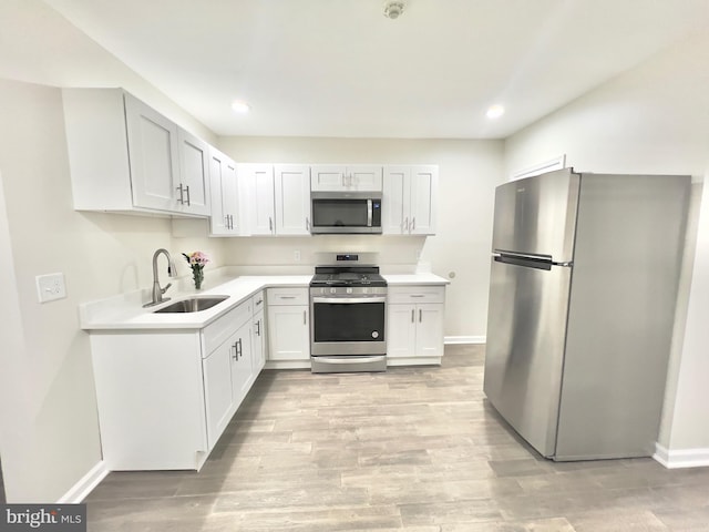 kitchen with white cabinetry, sink, stainless steel appliances, and light hardwood / wood-style floors