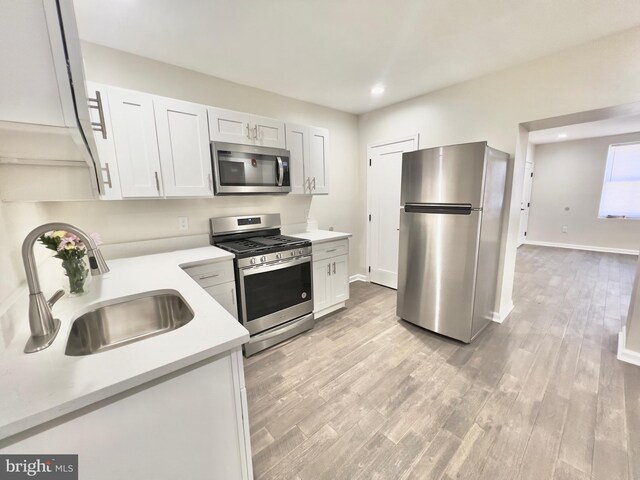 kitchen featuring sink, white cabinets, light wood-type flooring, and appliances with stainless steel finishes