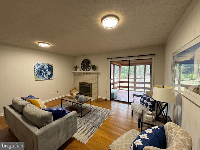 living room featuring hardwood / wood-style flooring, a textured ceiling, and a fireplace