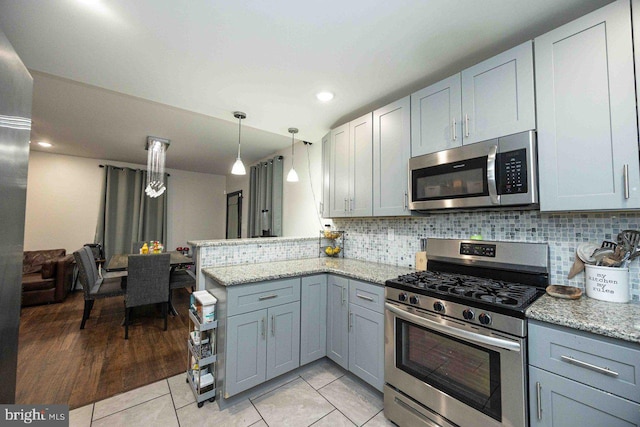 kitchen featuring kitchen peninsula, appliances with stainless steel finishes, backsplash, light stone counters, and light hardwood / wood-style floors