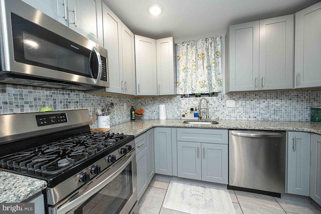 kitchen with tasteful backsplash, sink, light tile patterned floors, and stainless steel appliances