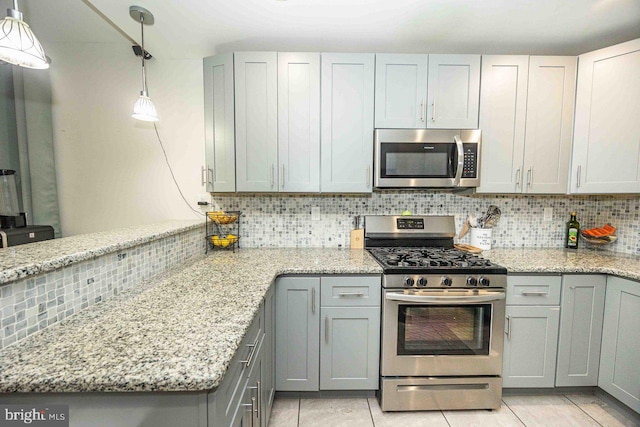 kitchen with gray cabinetry, hanging light fixtures, appliances with stainless steel finishes, and tasteful backsplash