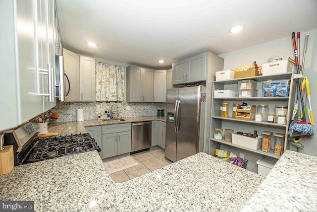 kitchen featuring sink, stainless steel appliances, tasteful backsplash, light stone counters, and kitchen peninsula