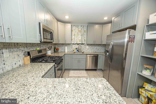 kitchen featuring tasteful backsplash, light stone counters, light tile patterned flooring, and appliances with stainless steel finishes