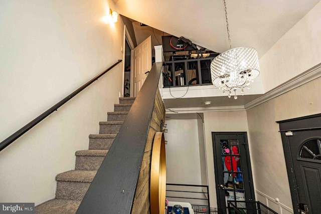 staircase featuring crown molding, a high ceiling, and an inviting chandelier