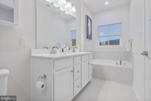 bathroom with tile patterned flooring, vanity, and tiled tub