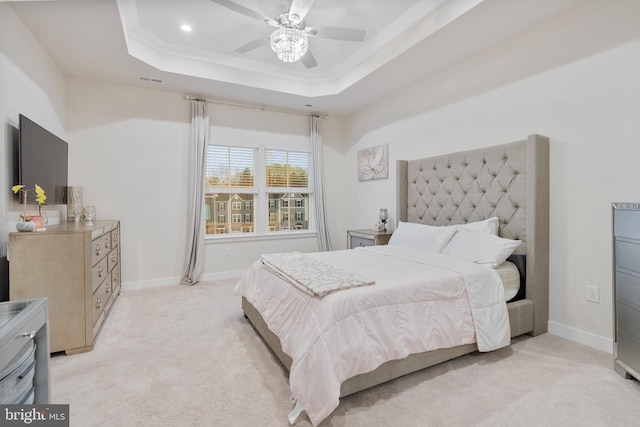 bedroom featuring a raised ceiling, ceiling fan, and light colored carpet