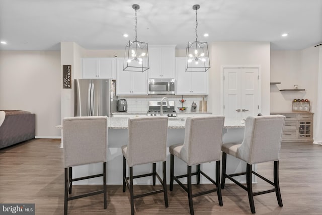 kitchen with stainless steel appliances, a kitchen island with sink, and a breakfast bar area