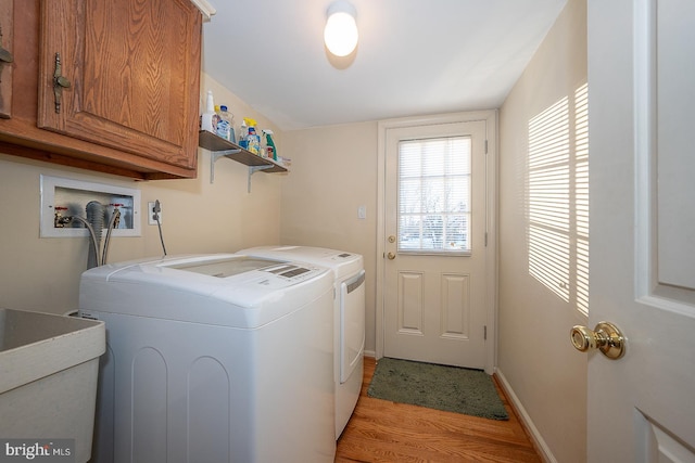 clothes washing area featuring cabinets, washing machine and dryer, light hardwood / wood-style floors, and sink