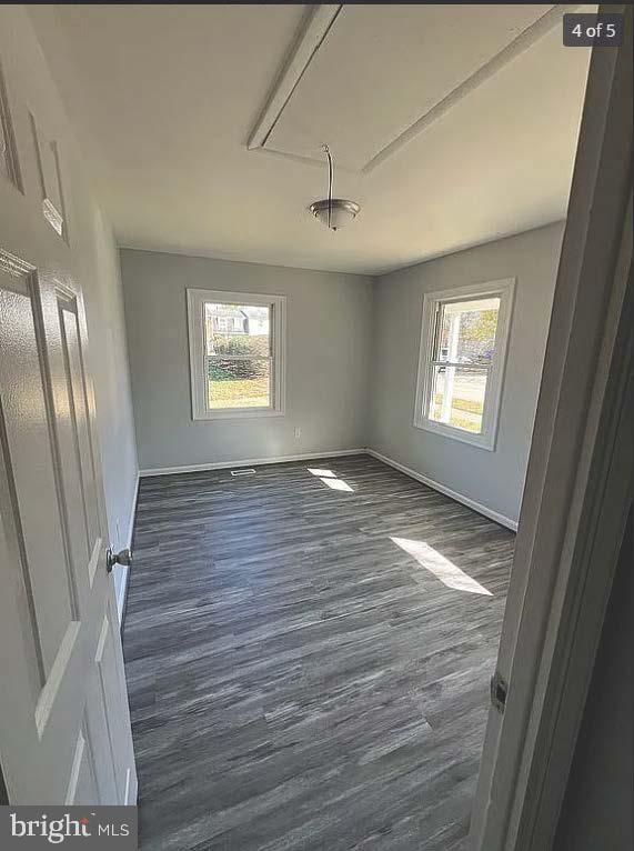 spare room with dark hardwood / wood-style floors and a healthy amount of sunlight