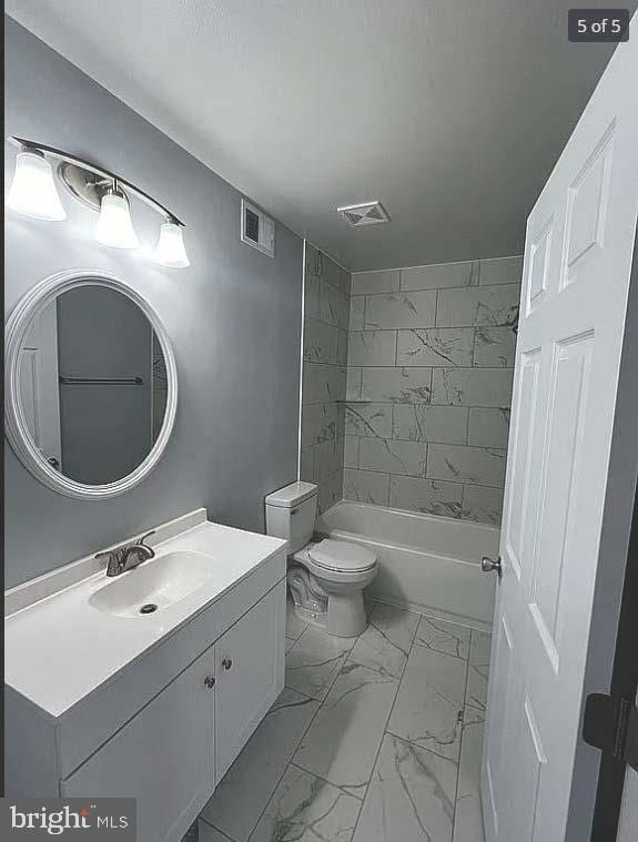 full bathroom with vanity, tiled shower / bath combo, and toilet