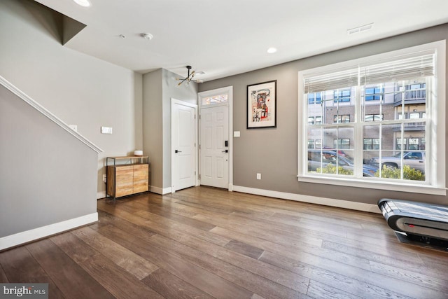 foyer entrance with wood-type flooring, a wealth of natural light, and a chandelier