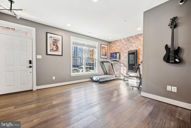 exercise room with wood-type flooring and a notable chandelier