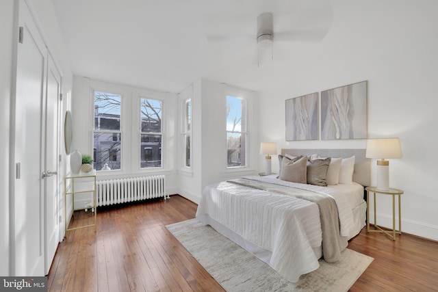 bedroom featuring ceiling fan, radiator heating unit, and wood-type flooring