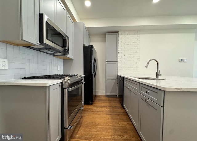 kitchen featuring gray cabinetry, sink, decorative backsplash, black appliances, and hardwood / wood-style flooring