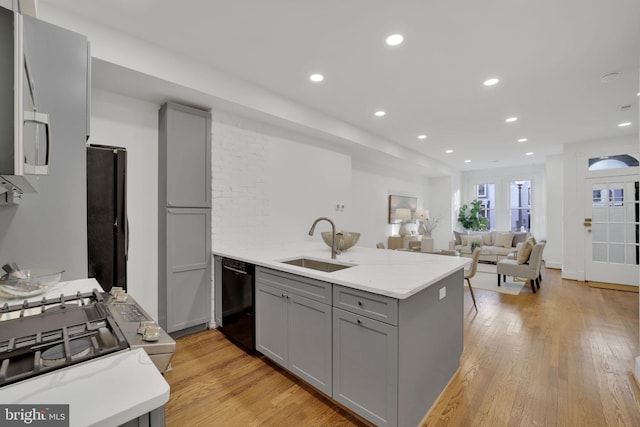 kitchen featuring light stone countertops, sink, light hardwood / wood-style floors, gray cabinets, and black appliances