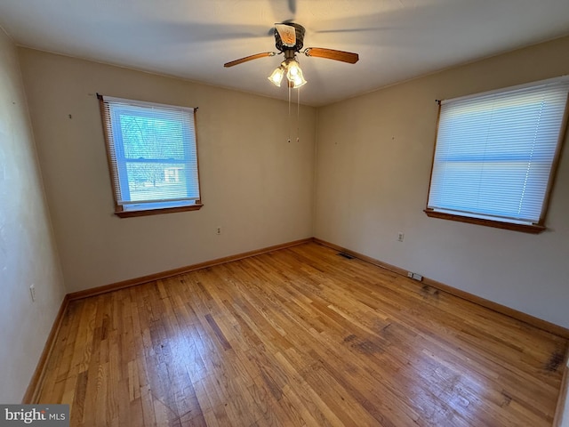 spare room featuring a ceiling fan, visible vents, baseboards, and light wood finished floors