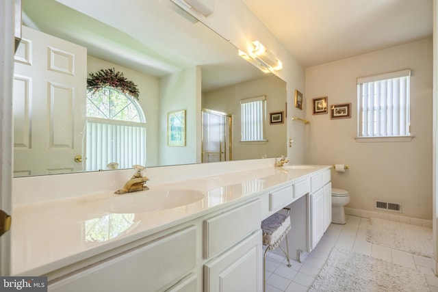 bathroom with tile patterned flooring, vanity, a shower with shower door, and toilet