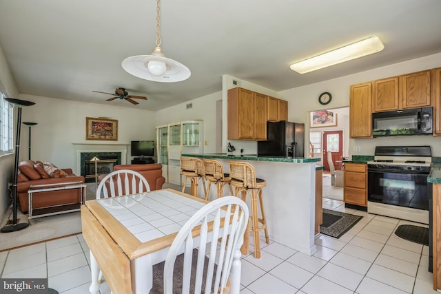 kitchen featuring a high end fireplace, light tile patterned floors, hanging light fixtures, and black appliances