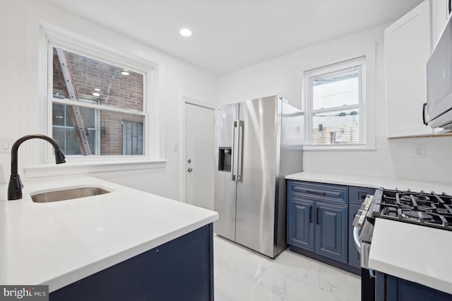 kitchen featuring backsplash, sink, stainless steel refrigerator with ice dispenser, white gas range, and blue cabinetry