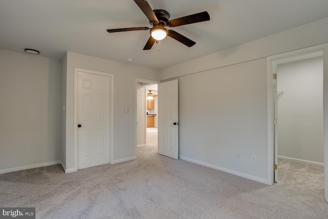 unfurnished bedroom featuring ceiling fan, light carpet, and a spacious closet