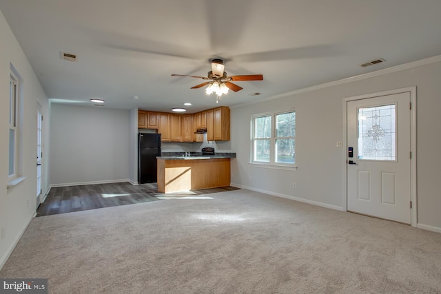 kitchen featuring carpet flooring, ceiling fan, black refrigerator, and crown molding